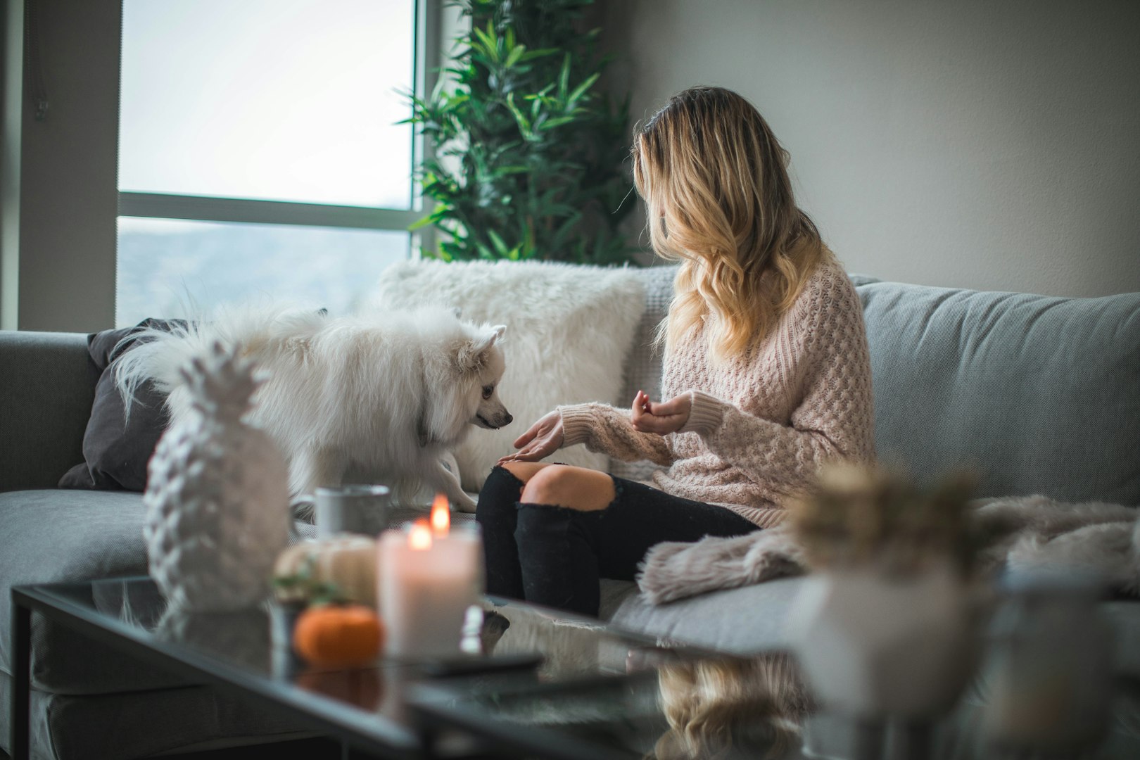 A Women sitting on her sofa with her pet dog