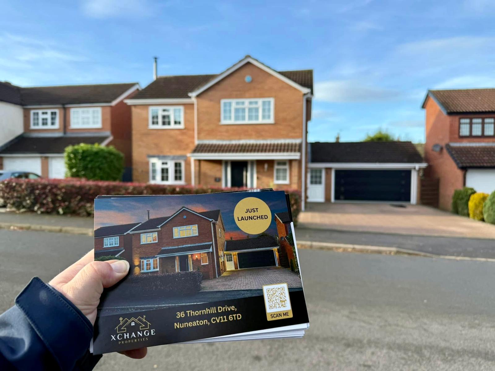 An estate agent hold a brochure in front of a proper for sale in Nuneaton