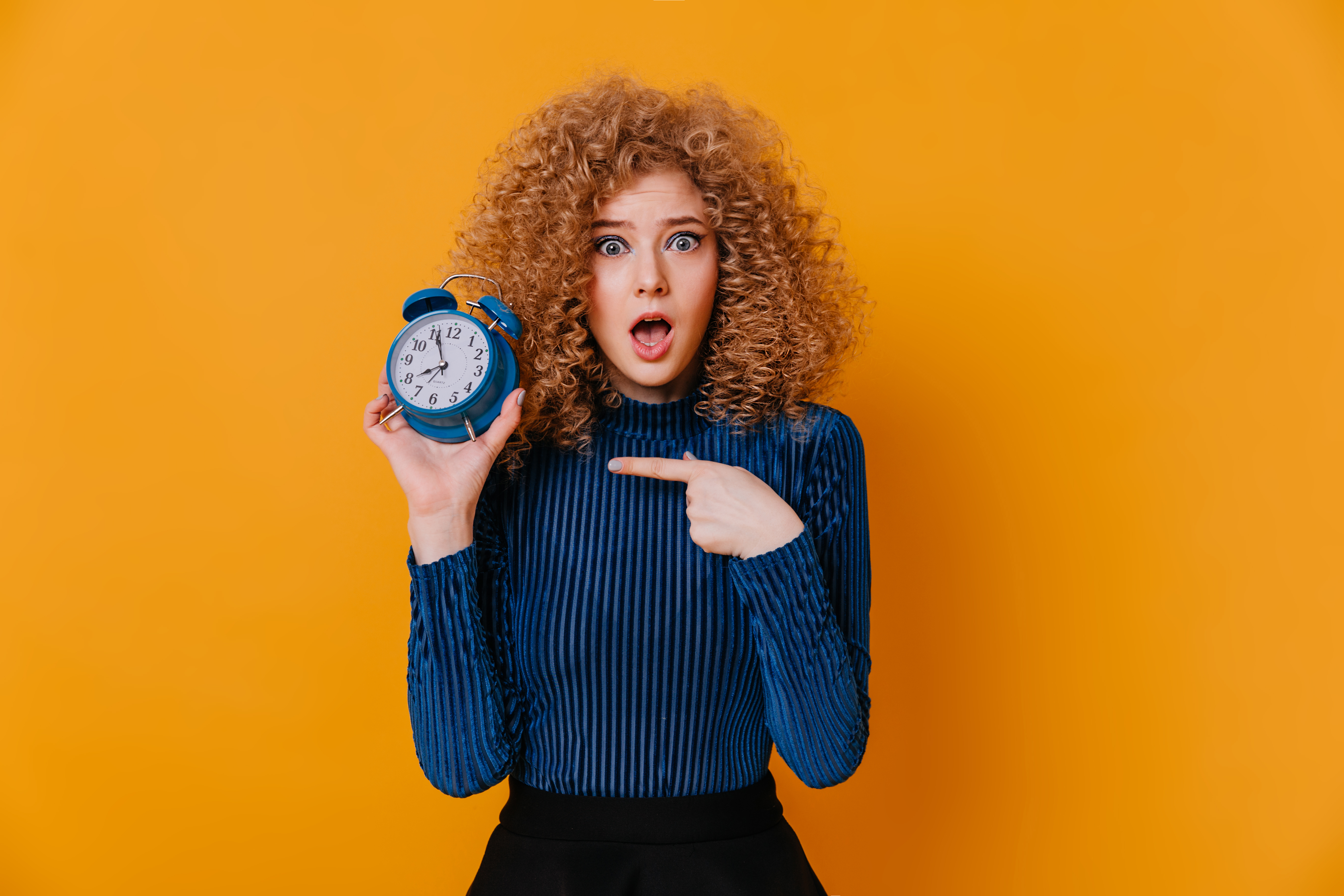 Red haired women with mouth open pointing at her clock