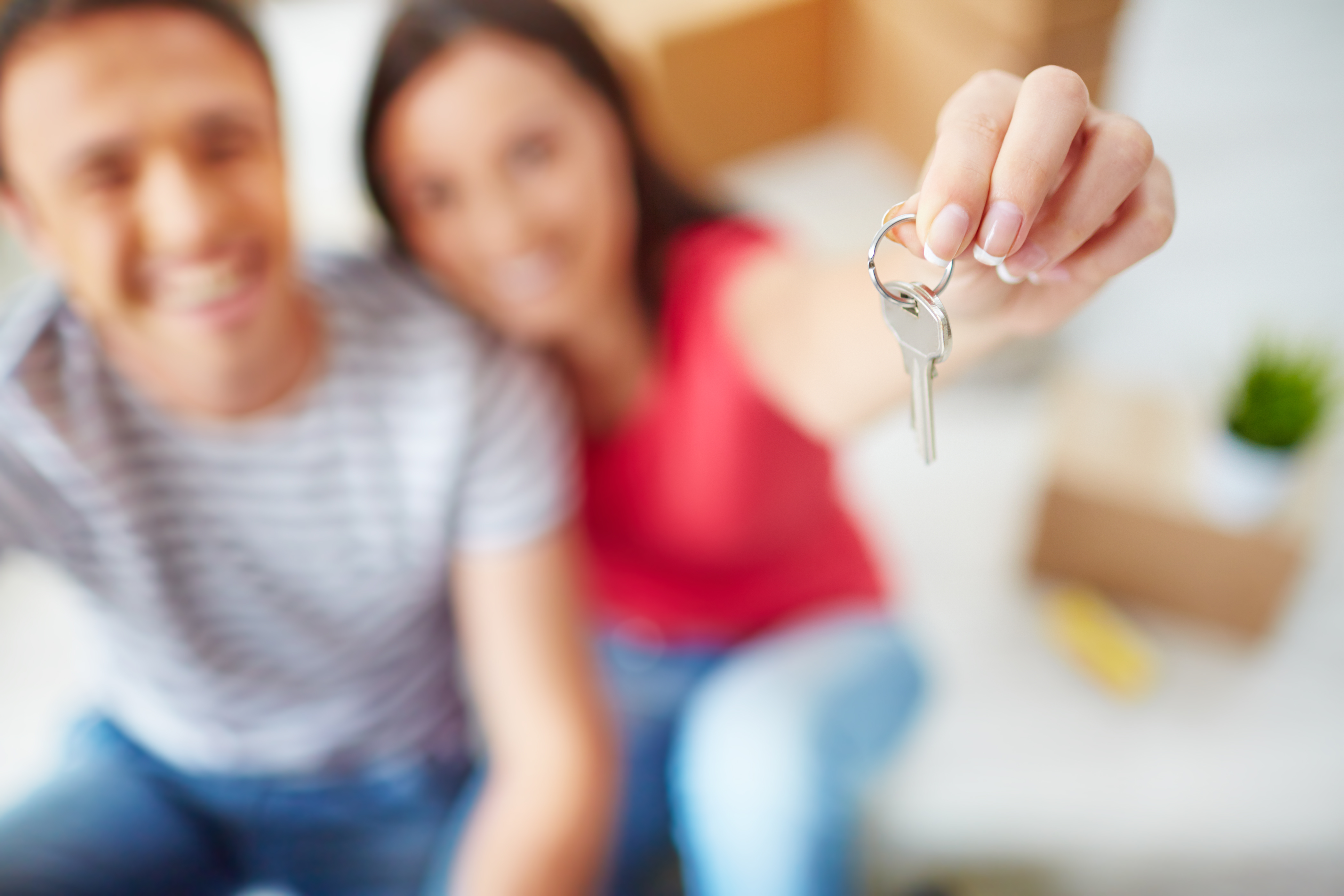 A man and women smiling. The women is holding the keys proudly in the new house